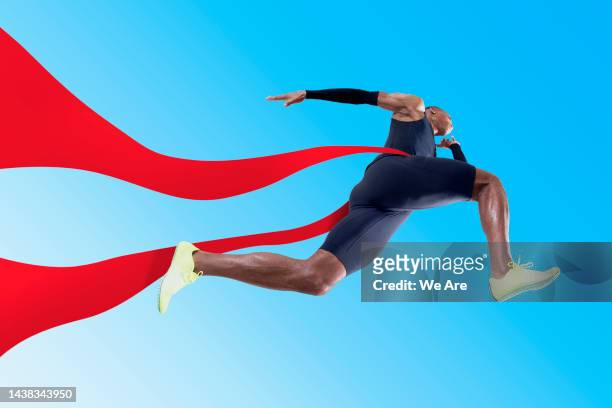 athlete running through red ribbon - アスリート ストックフォトと画像