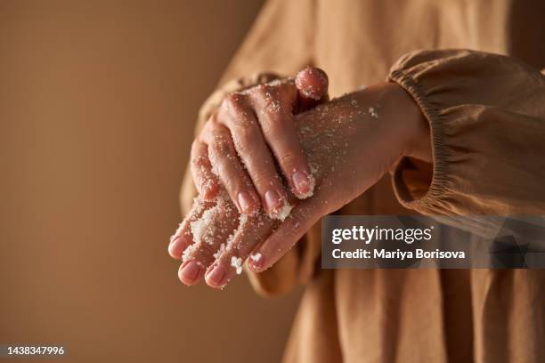 a girl in a beige dress rubs a natural sugar moisturizing scrub with her hand. - scrubs stock pictures, royalty-free photos & images