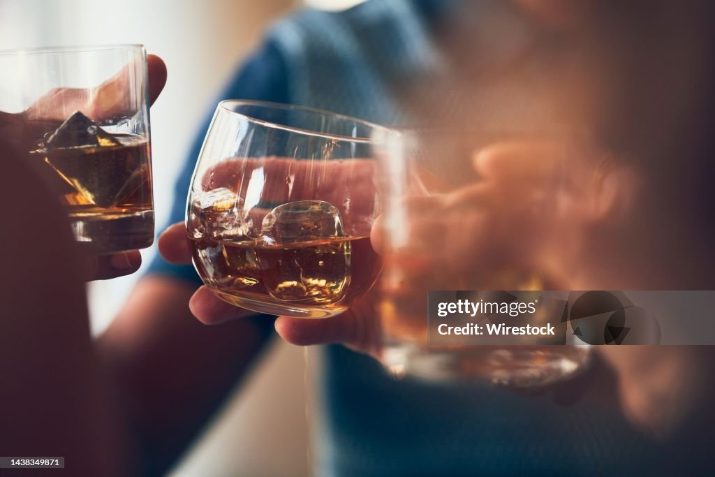 Closeup shot of many people clinking glasses with alcohol at a toast