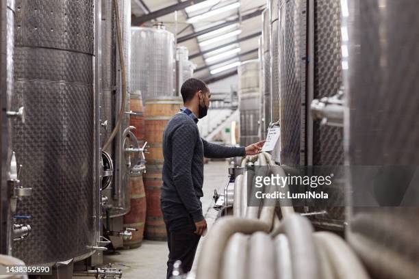 wine, production and covid with a black man at work in a cellar for fermentation in the winery industry. factory, manufacturing and plant with a male worker busy in an alcohol produce distillery - whiskey sour stock pictures, royalty-free photos & images