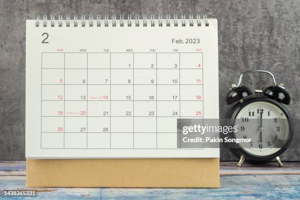 calendar desk 2023: february is the month for the organizer to plan and deadline with an alarm clock on the table against a concrete background. - february stock pictures, royalty-free photos & images
