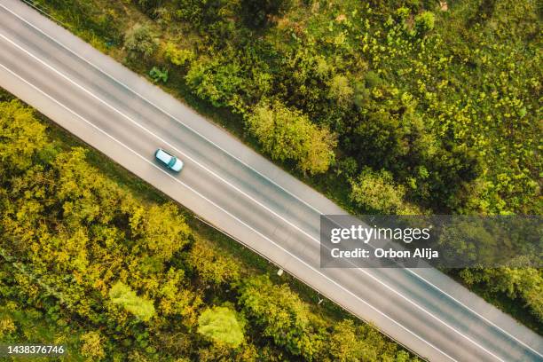 aerial view of  cars  along a road flanked by a green forest - urban road sign stock pictures, royalty-free photos & images