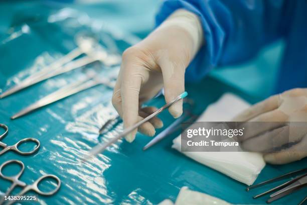 chirurgische instrumente und gaze werden von einer sterilen plastiktischdecke im operationssaal aufgenommen - zange chirurgische ausrüstung stock-fotos und bilder