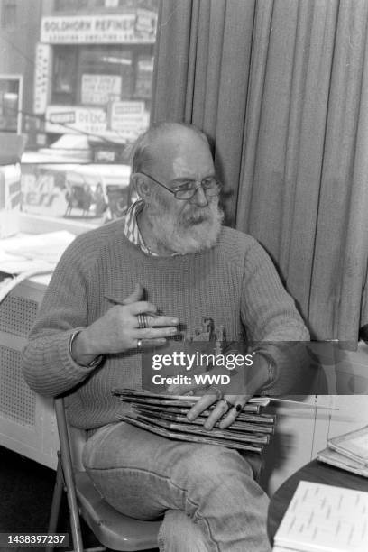 Writer Edward Gorey answers questions during an interview while signing his books.