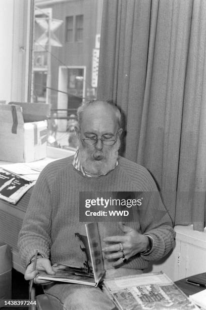 Writer Edward Gorey answers questions during an interview while signing his books.