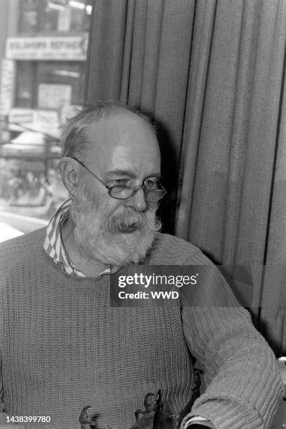 Writer Edward Gorey answers questions during an interview while signing his books.