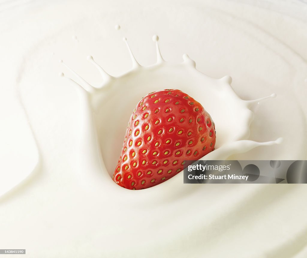 Strawberry splashing into cream