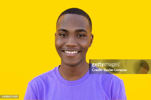 close up portrait of cheerful young black hispanic latin teenager man smiling at camera over yellow background - millennial people - spain teen face bildbanksfoton och bilder