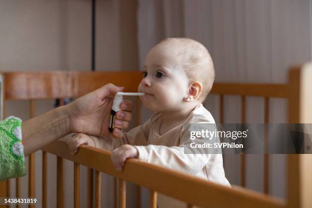 the baby takes vitamin d by mouth from a white bottle. - omega stock pictures, royalty-free photos & images