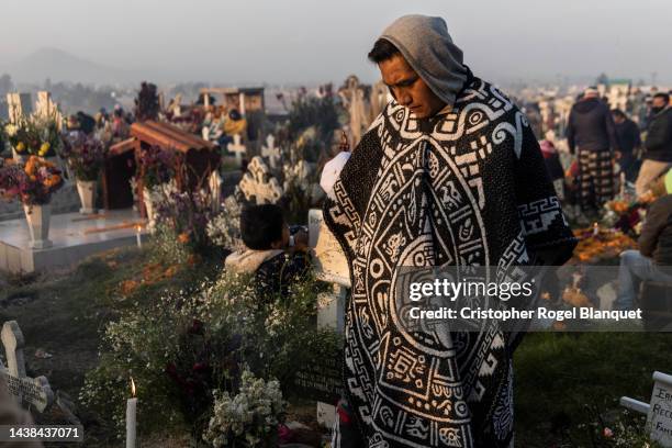 Man stands in front of the grave of his relatives during sunrise at the San Pablo Autopan cemetery during sunrise at the San Pablo Autopan cemetery...