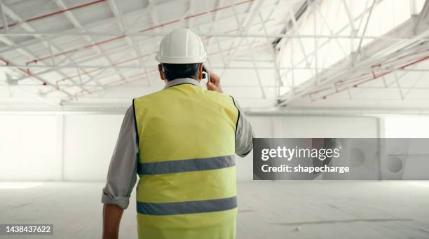 communication, construction and back view phone call with engineer talking in industrial building site. safety inspection, architect or contractor man on phone, construction worker in open warehouse. - quality control inspectors stock pictures, royalty-free photos & images