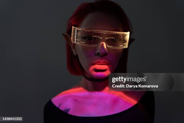 beautiful young woman in futuristic glasses, red and green light. digital age, smart glasses with neon light, the concept of the future, alien intelligence, digital technology and hacker attacks, computer games, virtual reality, disco night party. - big data therapie stock-fotos und bilder