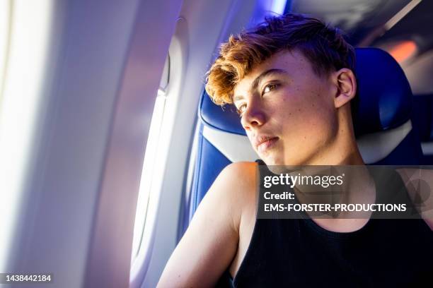 sad boy is looking out of a airplane window - teenage boy looking out window stock pictures, royalty-free photos & images