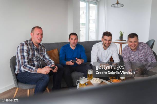 group of men playing video games against one another - man cave stock pictures, royalty-free photos & images