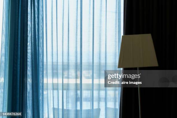 in the background a window with a light blue curtain and a cream-colored floor lamp. - lamp shade stockfoto's en -beelden