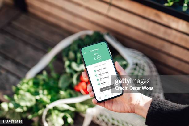 tracking online food and grocery delivery via mobile app on smart phone - groceries bag stock pictures, royalty-free photos & images