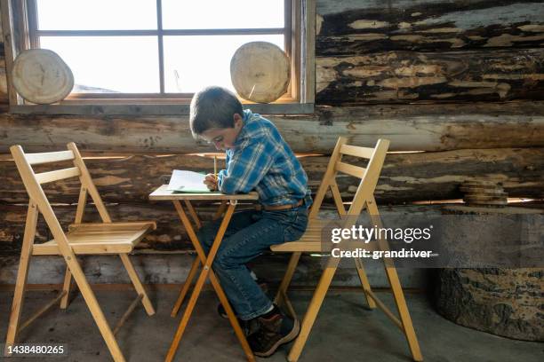young white boy doing homework in an old fashioned one-room school in the mountains with natural window light - small town america stock pictures, royalty-free photos & images