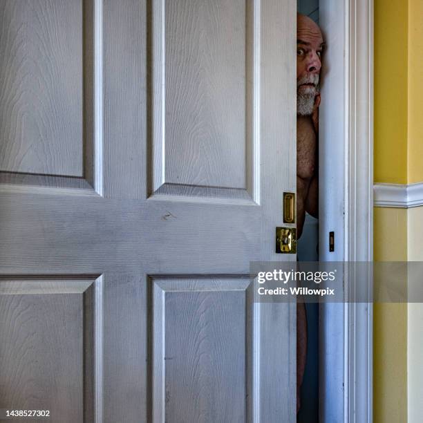 excited dirty old man peeking through cracked open doorway - stranger danger stock pictures, royalty-free photos & images