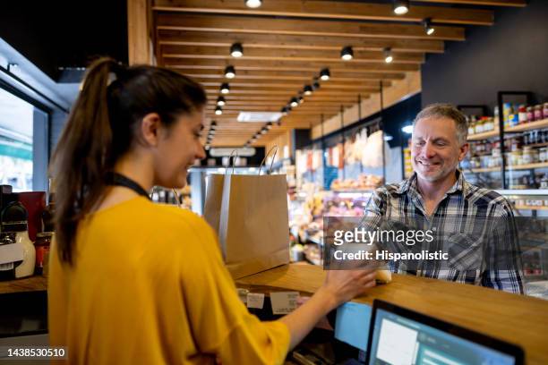 man making a contactless payment at the supermarket - cornershop stockfoto's en -beelden