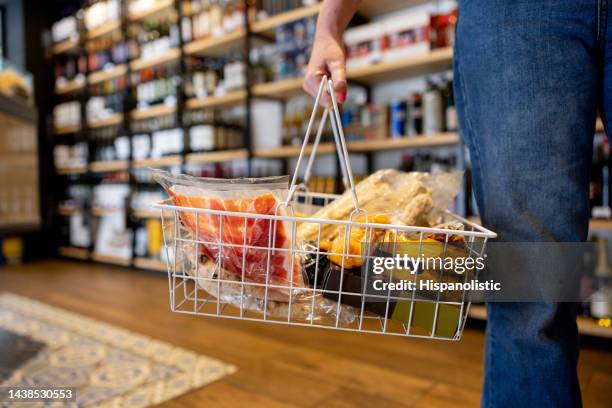nahaufnahme einer frau, die im supermarkt lebensmittel kauft und einen einkaufskorb trägt - einkaufskorb stock-fotos und bilder