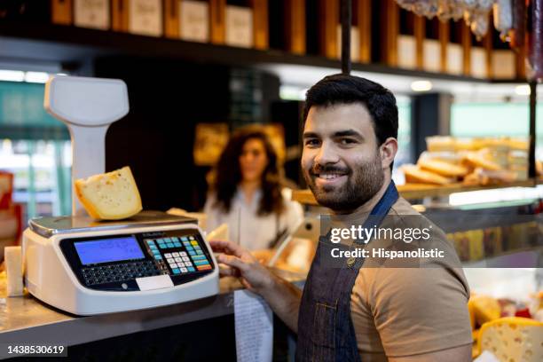 glückliche einzelhandelskauffrau beim käseverkauf im feinkostladen - cheesy salesman stock-fotos und bilder