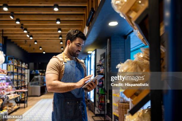 retail clerk working at a food store and doing the inventory - cornershop stock pictures, royalty-free photos & images