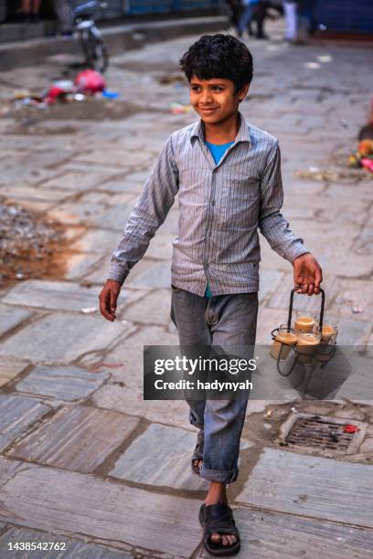 indian little boy selling chai on streets of kathmandu, nepal - trabalho infantil imagens e fotografias de stock