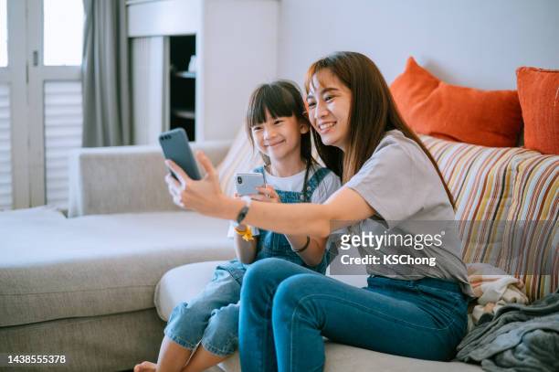 madre e figlia cinesi asiatici che fanno selfie e videochiamata a casa - chinese mothers day foto e immagini stock