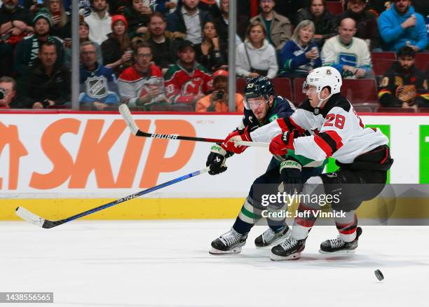 Damon Severson of the New Jersey Devils checks Bo Horvat of the Vancouver Canucks during their NHL game at Rogers Arena November 1, 2022 in...