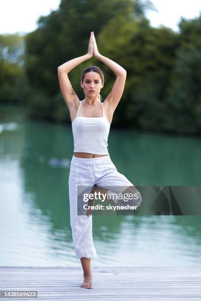 meditating in tree pose on a pier at lake! - tree position stock pictures, royalty-free photos & images