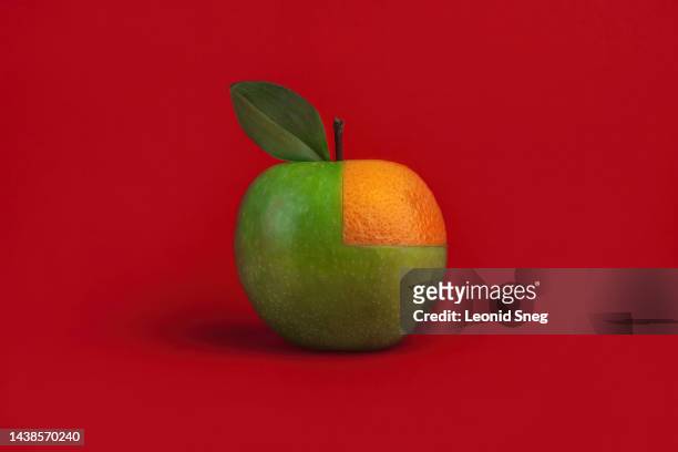 green apple with segment of orange fruit on red background. concept of cashback - apple credit card fotografías e imágenes de stock