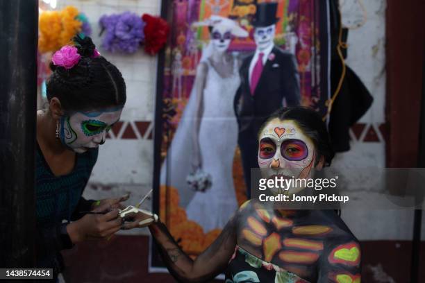 Young woman get her body painted as a skeleton for the festivities during 'Day of the Dead' celebrations on November 2, 2022 at San Andrés Mixquic...