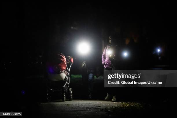 Residents of the residential district of Troieshchyna illuminate their way with flashlights of phones during an emergency blackout on November 1,...