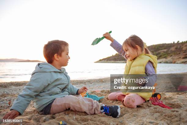 niña y niño jugando con juguete de plástico en la playa - 2 kid in a sandbox fotografías e imágenes de stock