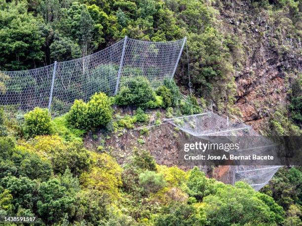 protected mountain road for rock and earth slides with large metal security meshes. - mudslide stock pictures, royalty-free photos & images