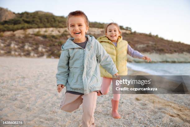 two children running on beach - sister day stock pictures, royalty-free photos & images