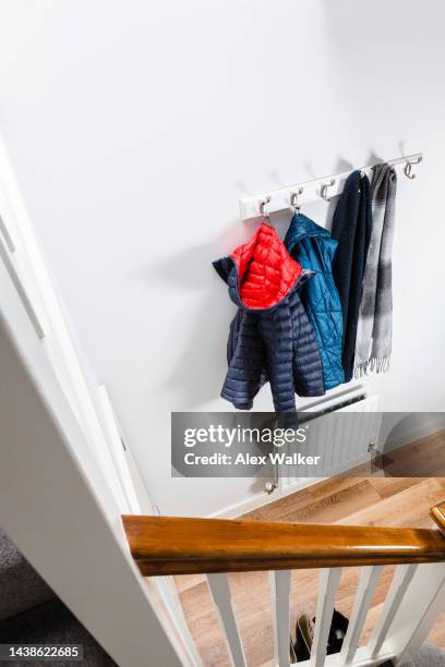 winter jackets and scarves hanging on coat hooks on a white wall in residential house hallway - draped scarf stock pictures, royalty-free photos & images