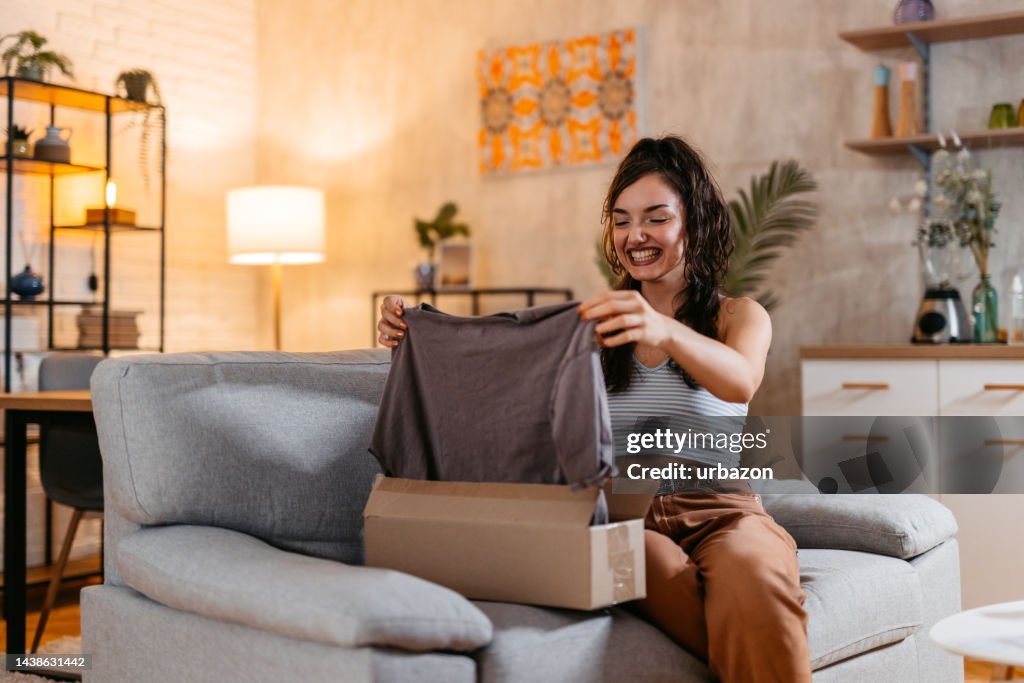 Mujer joven desempaquetando un paquete con una camisa nueva