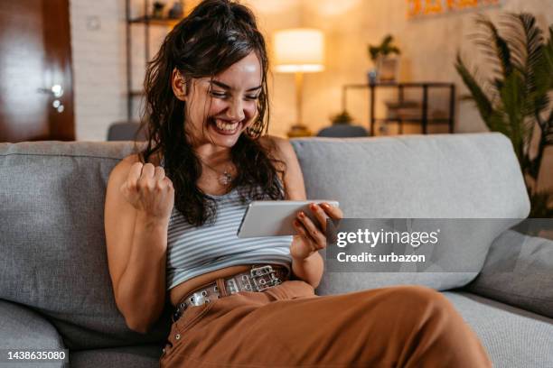 young woman playing video games on a smart phone at home - handheld video game stock pictures, royalty-free photos & images