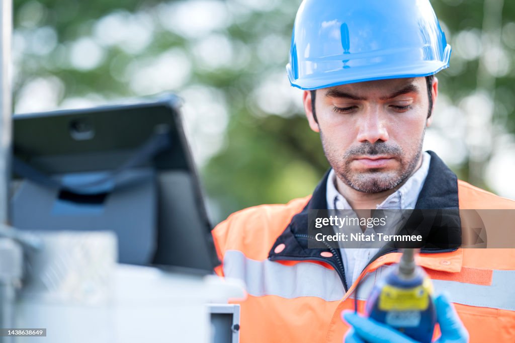 Sound Level Meters and Noise Dosimeters for Environmental Noise Monitoring. Male Engineer reading data from a sound level meter to measure noise and record data on a tablet computer during outdoor field operation.