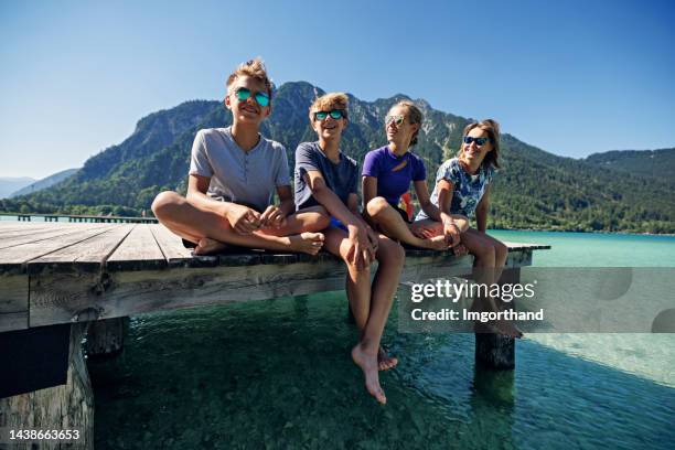 familie sitzt auf seebrücke in den österreichischen alpen. - boys relaxing stock-fotos und bilder