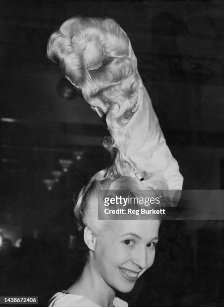Female model with her hair styled by Alex Joseph, with a high wire spring covered with white taffeta which is held in place by a black ribbon, a...