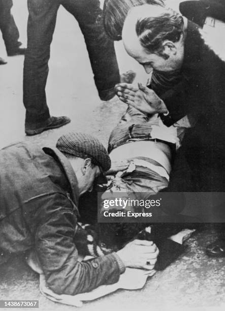 An priest administers the last rites to an dying rioter during the 'Bloody Sunday' riots which followed paratroopers opening fire on a protest march...