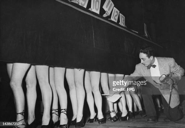Male judge taking measurements of the contestants' legs in a 'beautiful pair of legs' contest, held at the Salle Wagram in Paris, France, 1950. The...