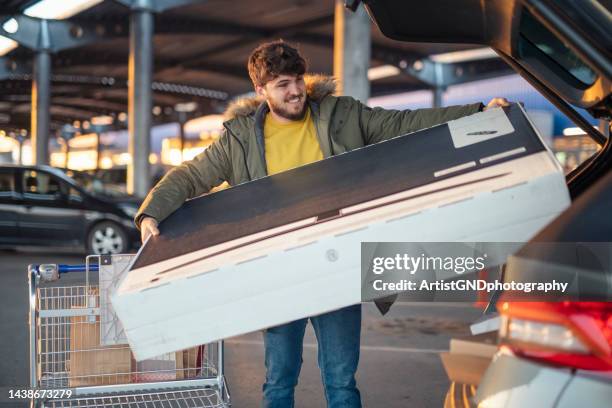 man loading tv set from black friday sale. - achterbak-van-auto stockfoto's en -beelden