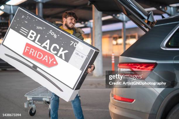 biggest black friday sale, loading tv bow in car. - black friday shopping stockfoto's en -beelden