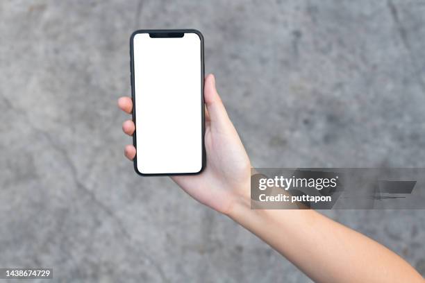 close-up of woman holding smartphone on polished cement background cropped hands using smartphone on polished cement mortar background concept of using technology in everyday life. - smartphones dangling stock pictures, royalty-free photos & images