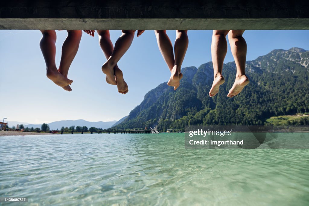 Familie sitzt auf Seebrücke in den österreichischen Alpen.