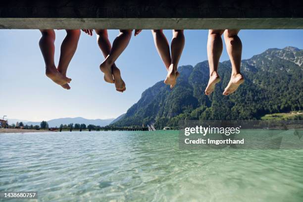 family sitting on pier on lake in austrian alps. - bergsteiger stockfoto's en -beelden