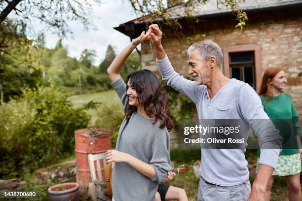 senior man dancing with young woman on a garden party - father son outdoor celebration photos et images de collection